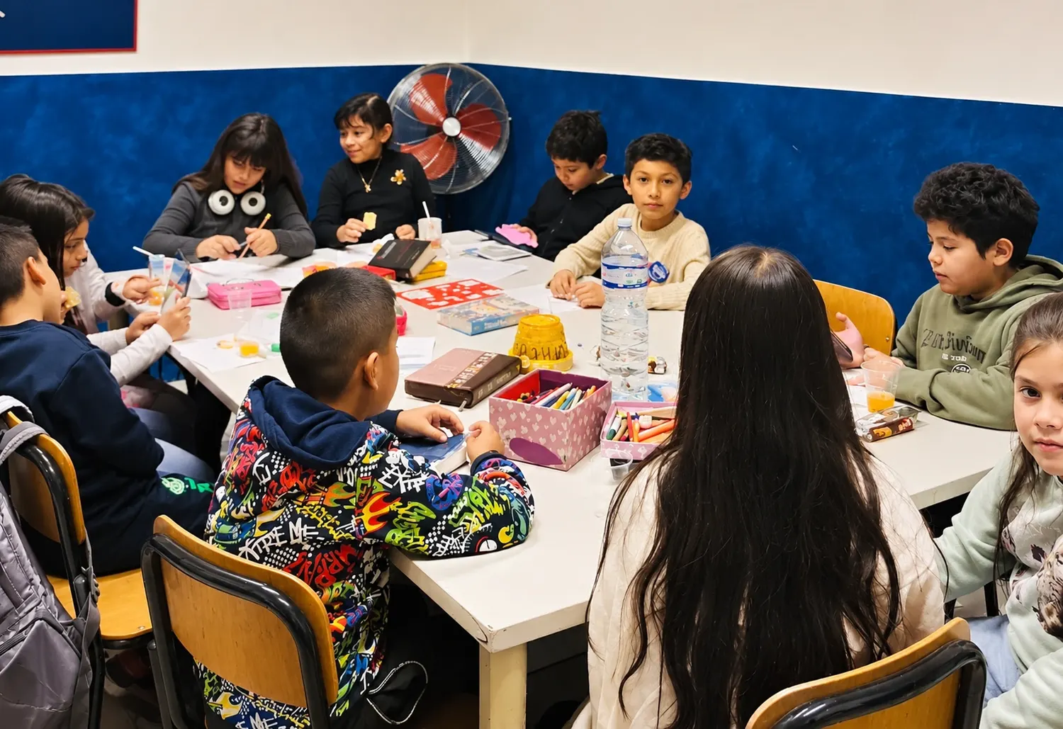 Niños en la mesa con colores y manualidades durante la Escuela Bíblica